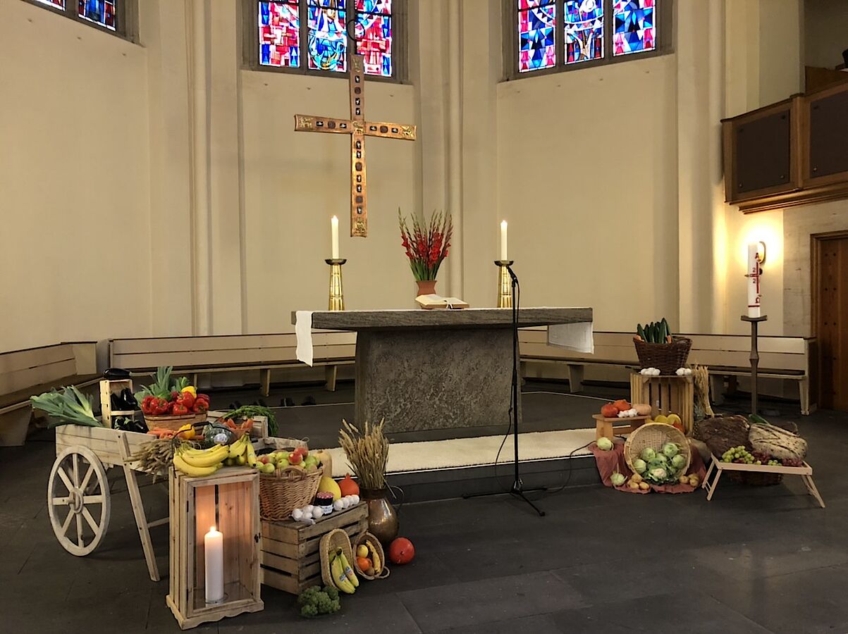 Kirchenaltar geschmückt mit Erntegaben wie Obst, Gemüse und Brot.