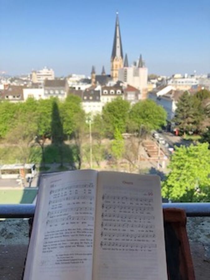 Aufgeschlagenes Gesangbuch auf einem Balkon mit Blick auf die Kreuzkirche.