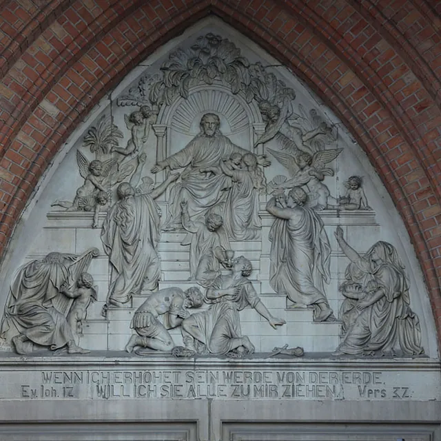 Steinrelief von Jesus mit Nachfolgern über einem Kirchenportal.
